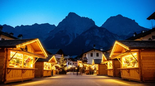 Vista panoramica dei mercatini di Natale dell'Alto Adige con casette di legno illuminate e montagne innevate sullo sfondo